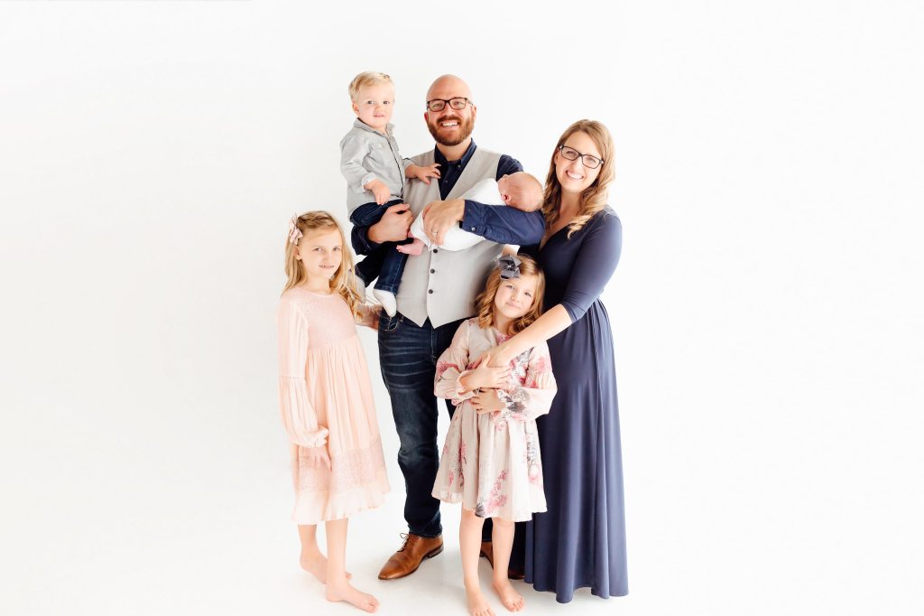 Family of six in navy and pink with a white background.